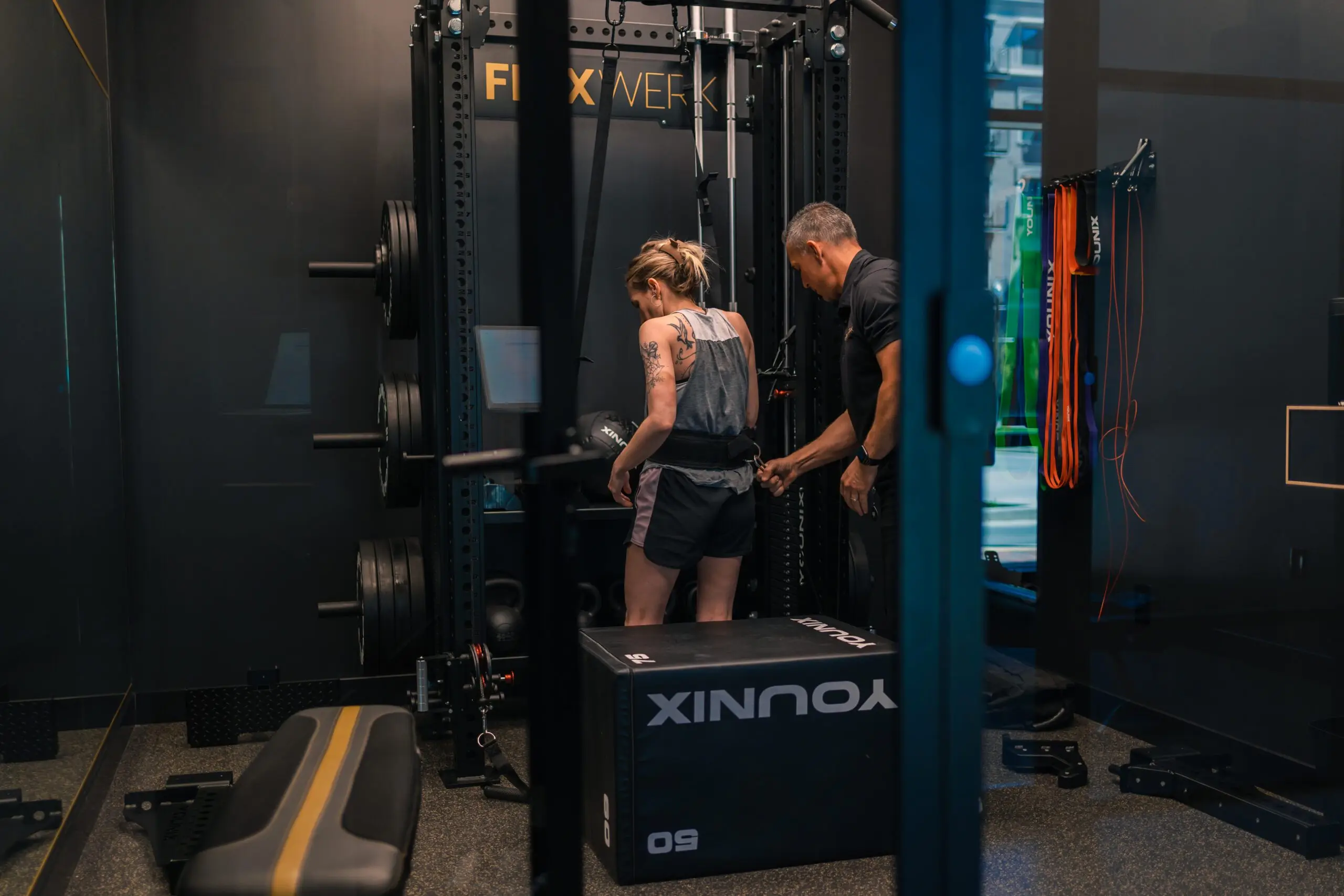 A FlexWerk personal trainer beside a client at a cable station in a private suite