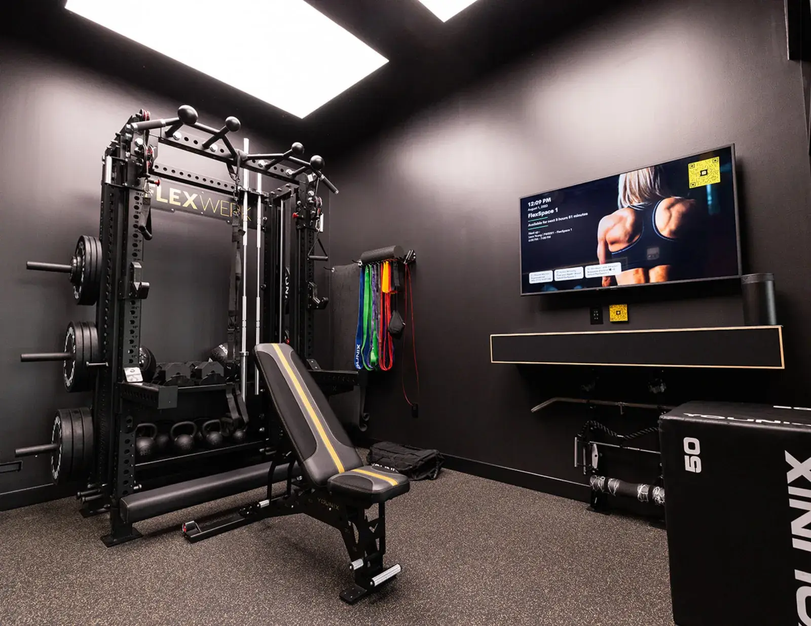 A private FlexWerk suite with a rack, adjustable bench, plyo box and wall screen