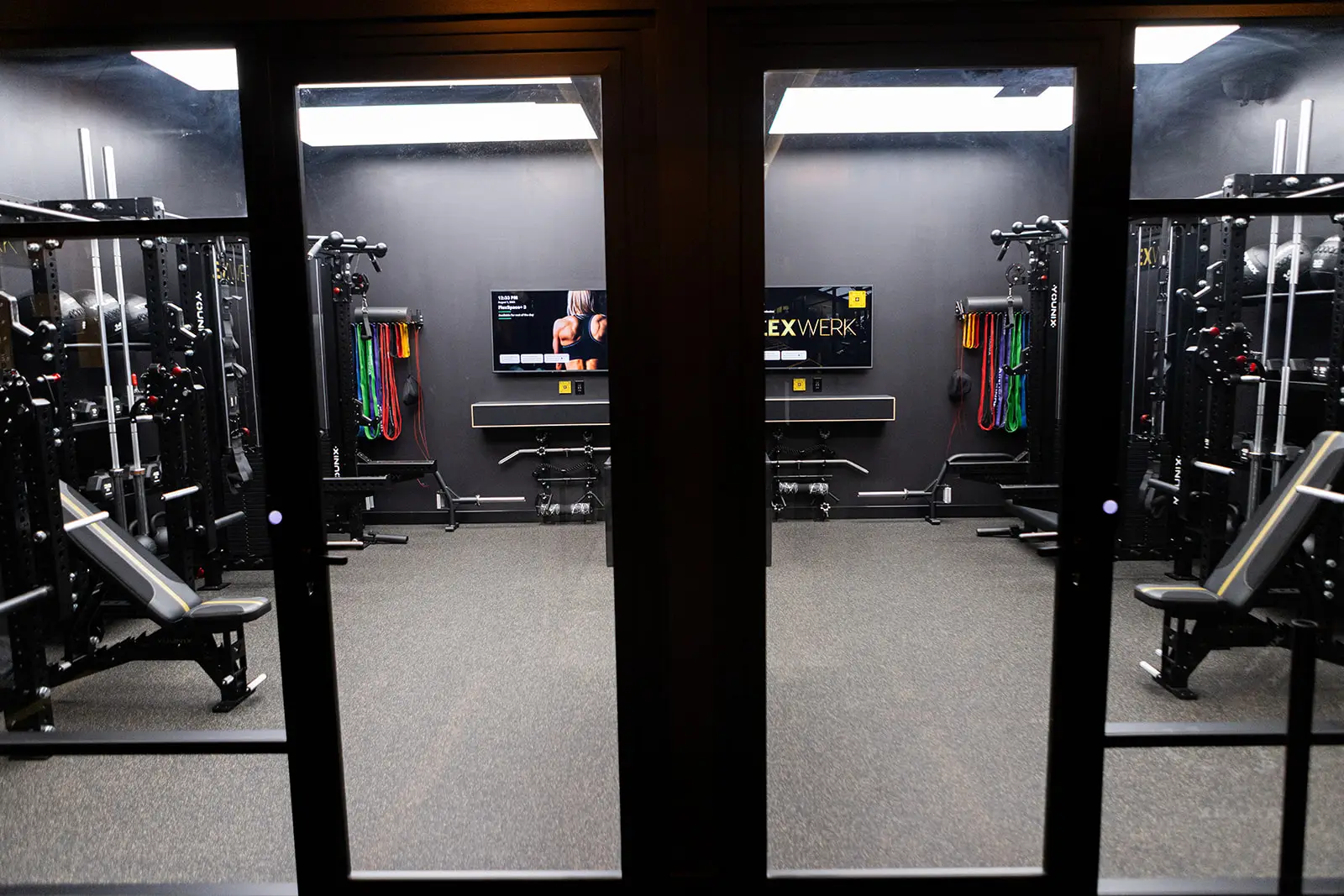 View through glass doors into a FlexWerk private suite with a rack and bench