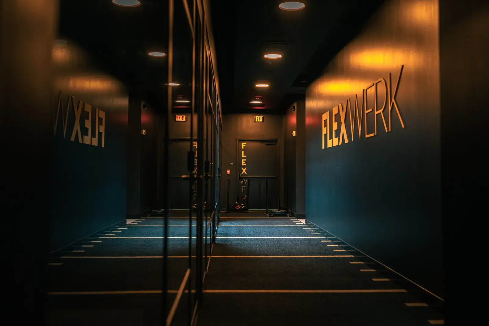 A dim indoor turf corridor with illuminated FlexWerk lettering on the wall