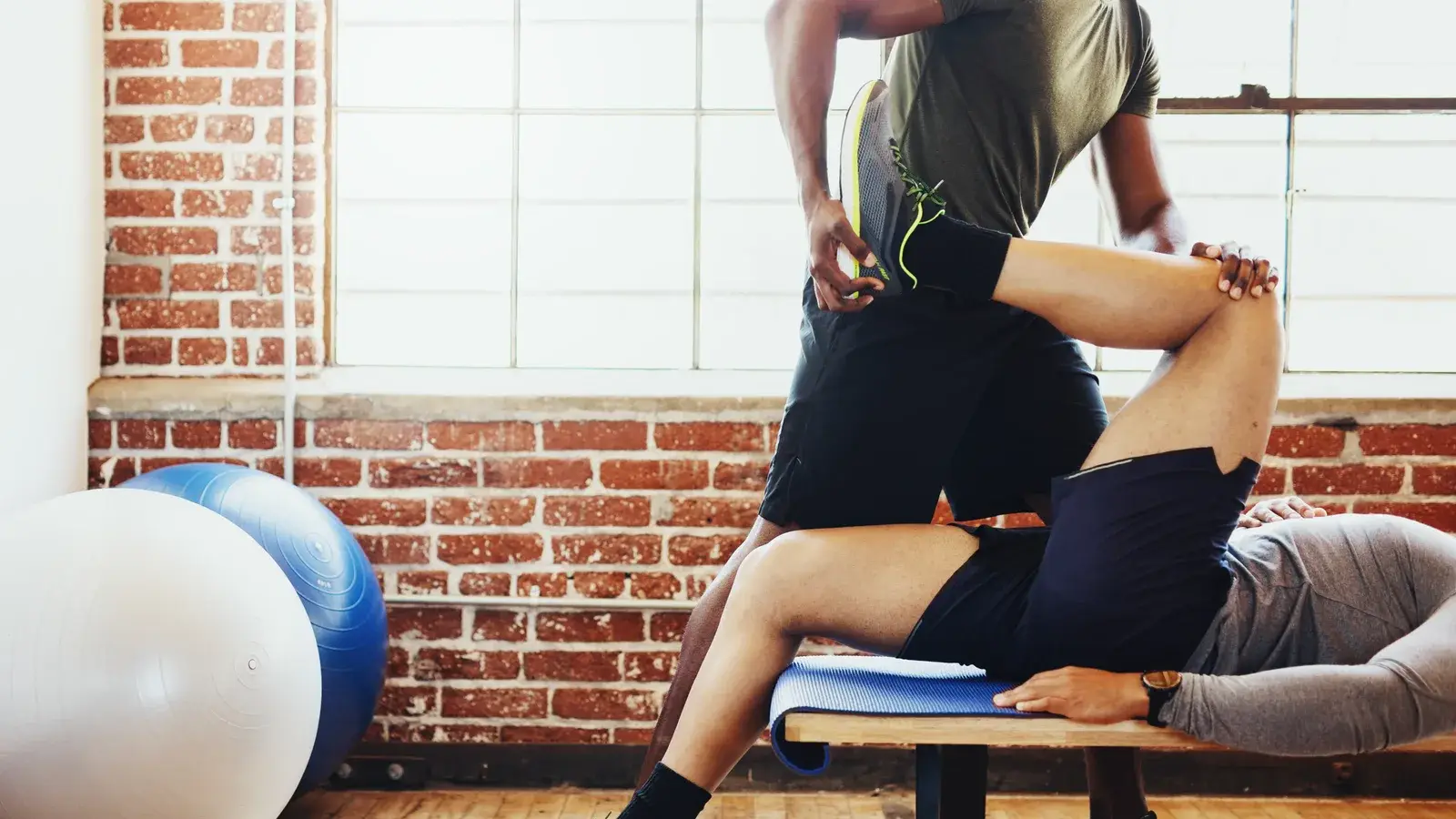 A practitioner applies a hip and leg stretch to a person lying on a table